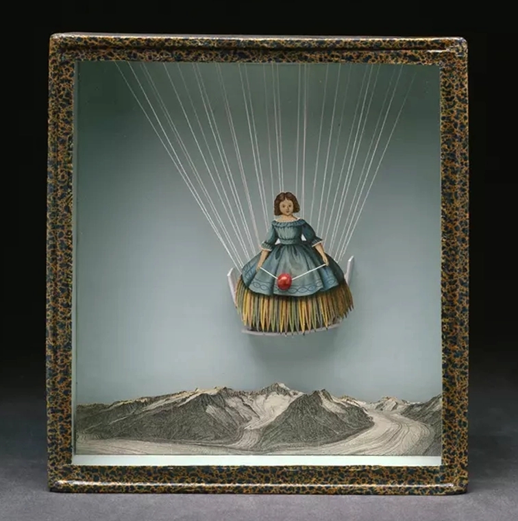One of Joseph Cornell's memory boxes, titled Tilly Losch. Features a paper doll floating from string s in the air above a mountain range.